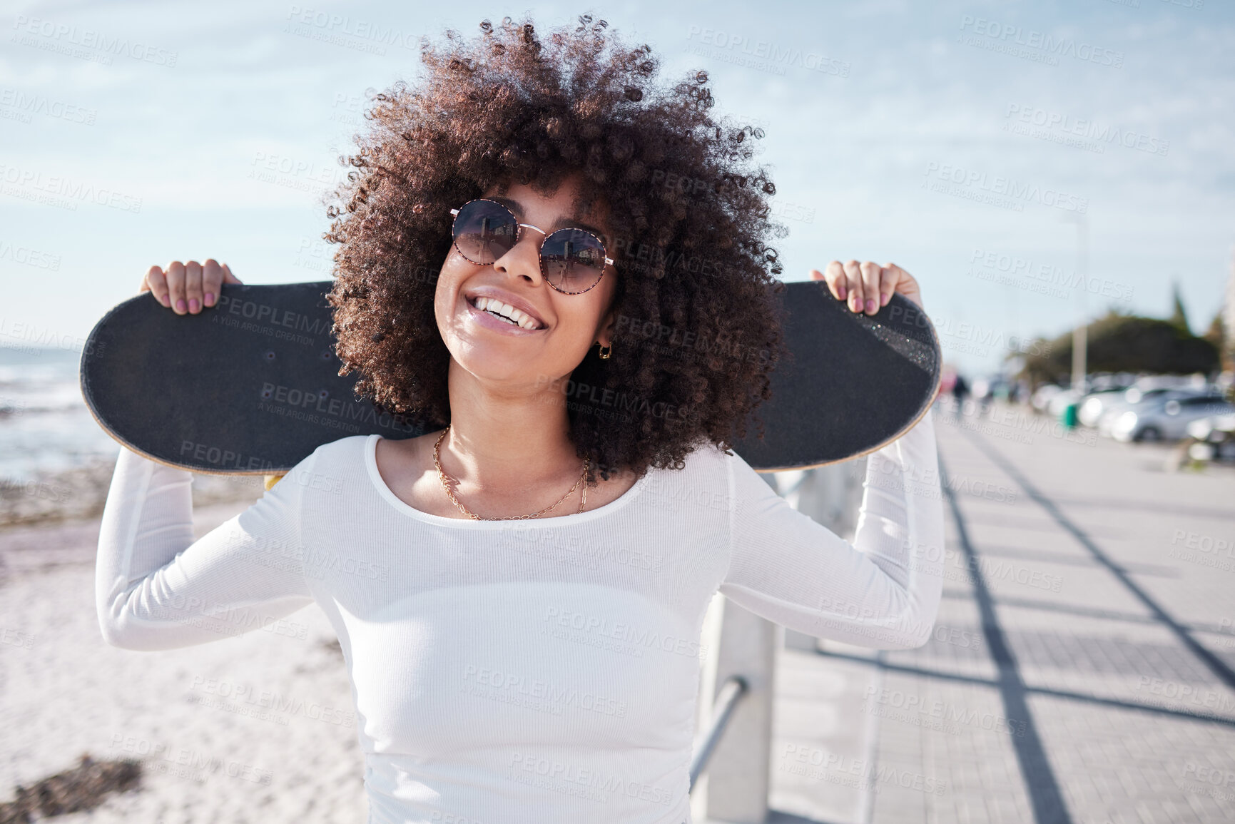 Buy stock photo Happy, summer and black woman by ocean with skateboard for weekend, holiday and vacation in trendy style. Fashion, laughing and person skateboarding for activity, freedom and adventure by seaside