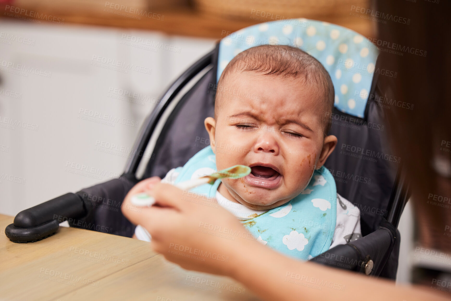 Buy stock photo Upset, crying and mother feeding baby in home with spoon for nutrition, health or wellness meal in high chair. Tired, sad and frustrated infant eat with mom for child development and growth at house.