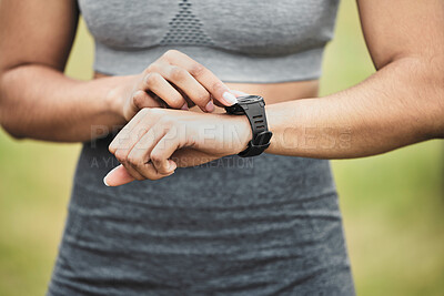 Buy stock photo Cropped shot of an unrecognizable young female athlete checking her smartwatch while exercising outside