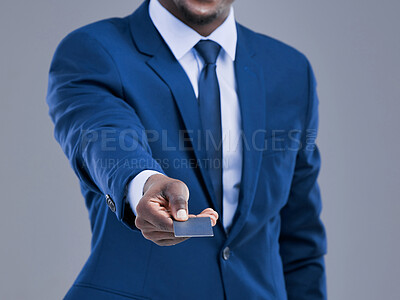 Buy stock photo Cropped shot of an unrecognizable businessman holding out his credit card in studio against a grey background