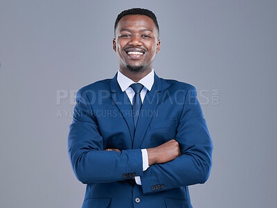 Buy stock photo Cropped portrait of a handsome young businessman standing with his arms crossed in studio against a grey background