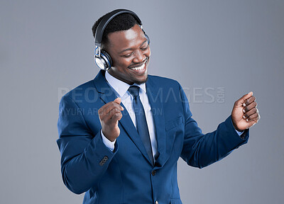 Buy stock photo Cropped shot of a handsome young businessman using his headphones to listen to music in studio against a grey background