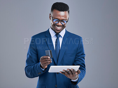 Buy stock photo Cropped shot of a handsome young businessman using a tablet to do some online banking in studio against a grey background