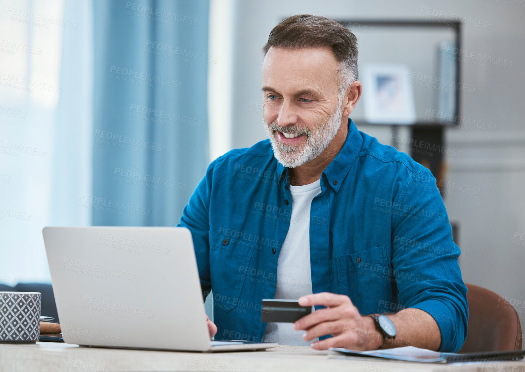 Buy stock photo Shot of a mature businessman using his laptop to make online card payments