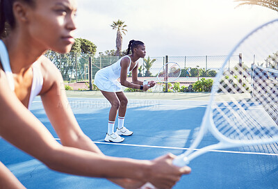 Buy stock photo Shot of two attractive young women standing together while playing tennis