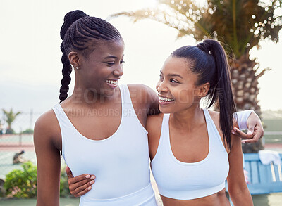 Buy stock photo Shot of two attractive women standing together while playing tennis outside