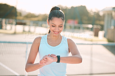 Buy stock photo Shot of an attractive young woman standing alone and checking her watch during tennis practise