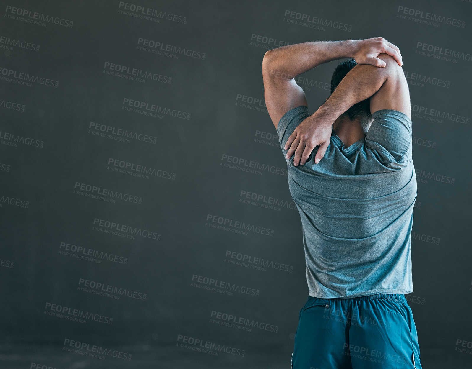 Buy stock photo Rearview shot of an unrecognizable young male athlete warming up against a grey background