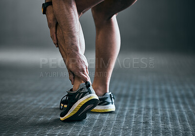 Buy stock photo Rearview shot of an unrecognizable young male athlete holding his ankle in pain against a grey background