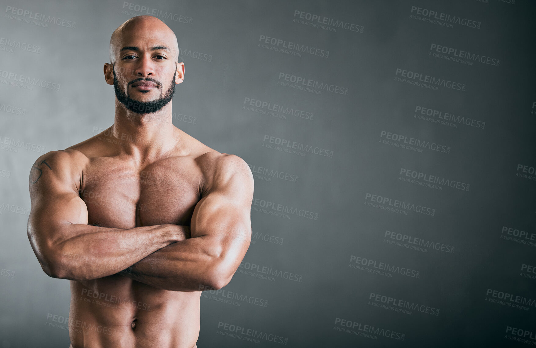 Buy stock photo Cropped portrait of a handsome young male athlete standing shirtless with his arms folded against a grey background