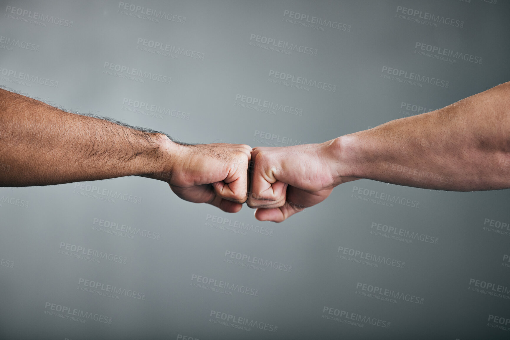 Buy stock photo Cropped shot of two unrecognizable male athletes fist bumping against a grey background
