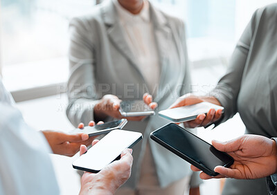 Buy stock photo Cropped shot of a group of unrecognizable businesspeople holding their cellphones while standing in the office