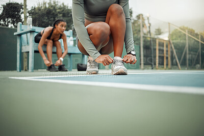 Buy stock photo Cropped shot of an unrecognizable young female athlete tying her laces during an outdoor workout with a friend in the background
