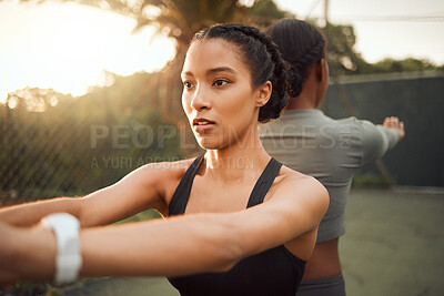 Buy stock photo Cropped shot of two attractive young female athletes warming up outside before beginning their workout
