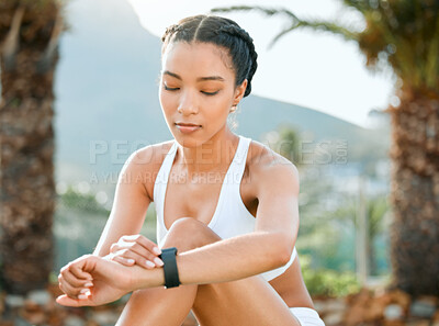 Buy stock photo Shot of a sporty young woman checking her wristwatch while playing tennis on a court