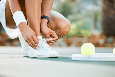 Buy stock photo Shot of a sporty young woman tying her laces while playing tennis on a court