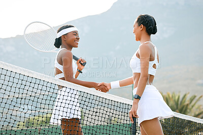 Buy stock photo Shot of two sporty women shaking hands while playing tennis together on a court
