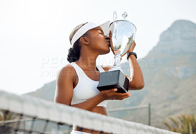 Buy stock photo Shot of a sporty young woman kissing a trophy that she won in a tennis match