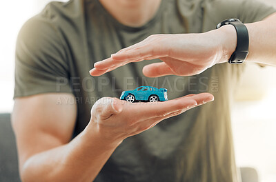 Buy stock photo Shot of a unrecognizable male covering a toy car with his hands at home