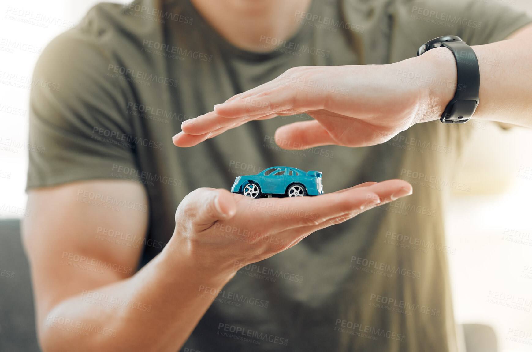 Buy stock photo Shot of a unrecognizable male covering a toy car with his hands at home