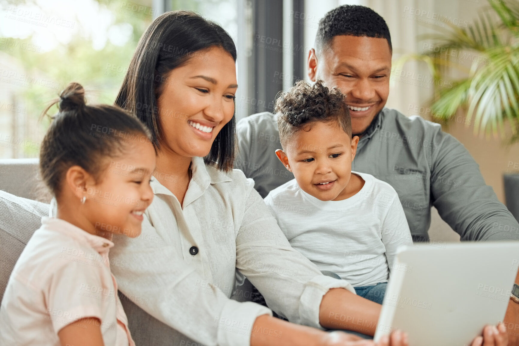 Buy stock photo Shot of a young family happily bonding while using a  digital tablet together on the sofa at home