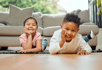 Buy stock photo Portrait of two young siblings lying on the floor together at home