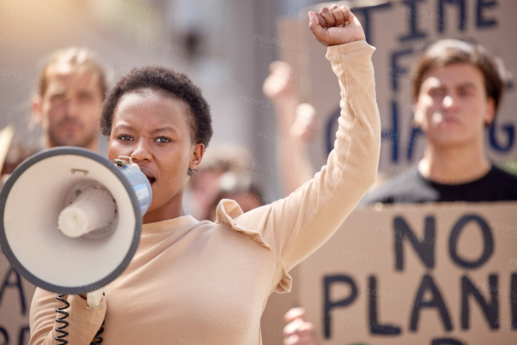 Buy stock photo Shot of a young woman speaking through a megaphone at a protest