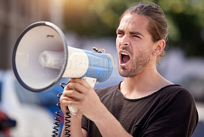 Buy stock photo Shot of a young man using a megaphone at a protest rally