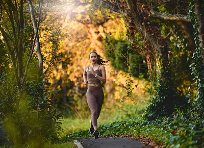 Buy stock photo Woman, fitness and running in forest for cardio exercise, workout or training in the nature outdoors. Female person, athlete or runner exercising for healthy wellness, marathon or run in the woods