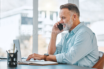 Buy stock photo Shot of a mature businessman sitting alone in his office while using his laptop and cellphone