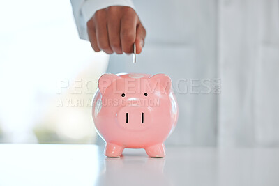 Buy stock photo Shot of an unrecognizable man depositing coins into his piggy bank in a office