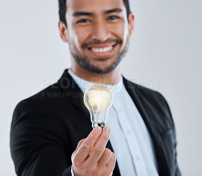 Buy stock photo Shot of a young man holding a light bulb against a grey background