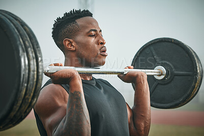 Buy stock photo Shot of a muscular young man exercising with a barbell outdoors