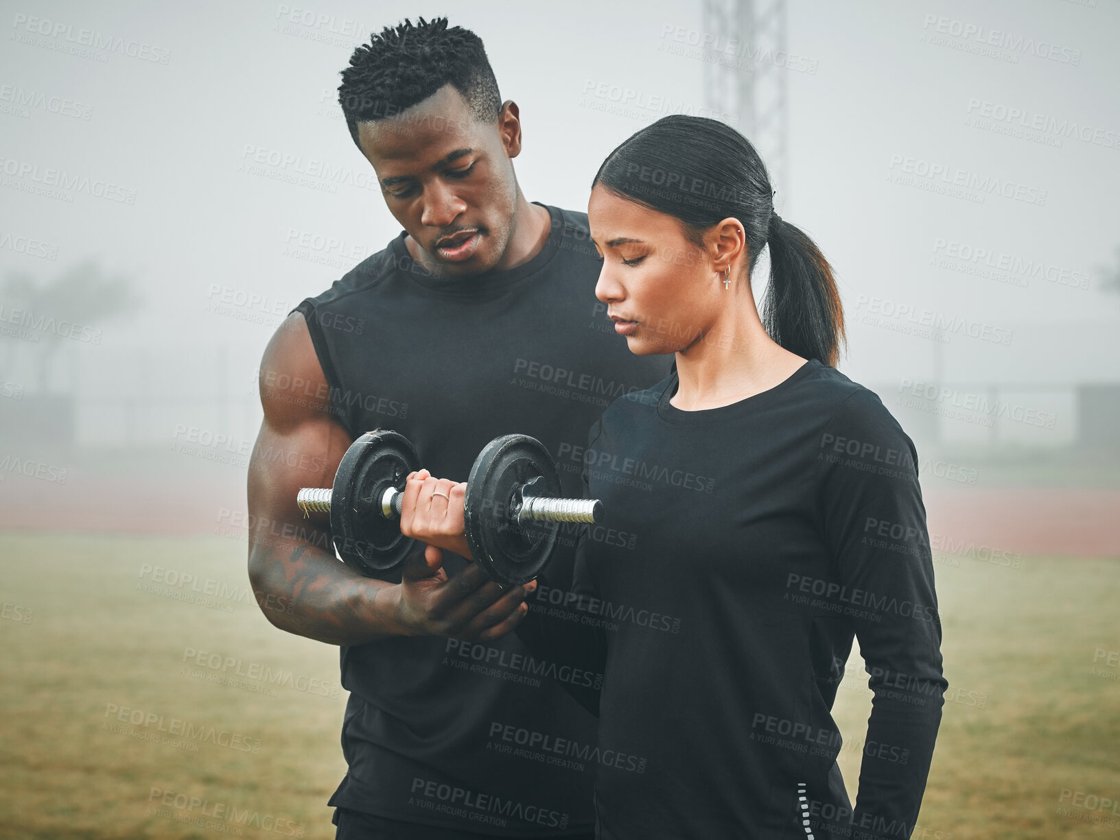 Buy stock photo Sports, weights and personal trainer with woman in nature for arm strength, muscles and tone. Fitness, fog and male instructor helping female athlete with dumbbell for lifting exercise in field. 