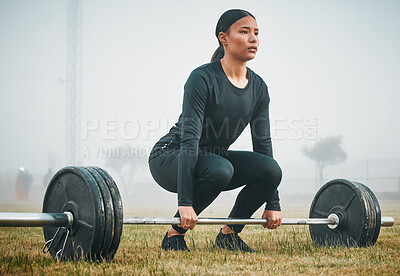 Buy stock photo Shot of a sporty young woman exercising with a barbell outdoors