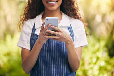 Buy stock photo Shot of a florist using her smartphone to send a text message
