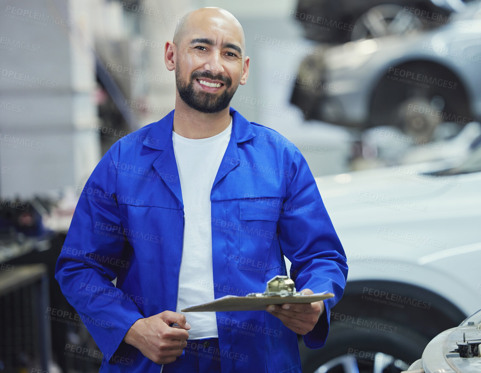 Buy stock photo Cropped portrait of a handsome young male mechanic working on the engine of a car during a service