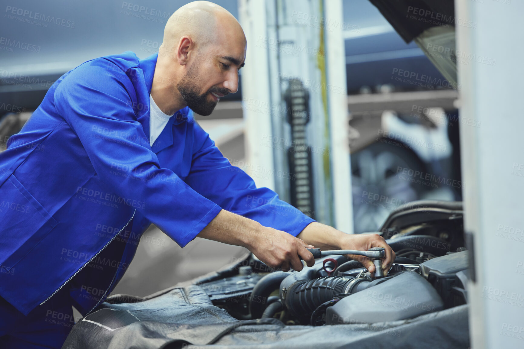 Buy stock photo Cropped shot of a handsome young male mechanic working on the engine of a car during a service