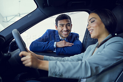 Buy stock photo Cropped shot of an attractive young woman sitting in a new car while speaking to a handsome male car salesman about a deal