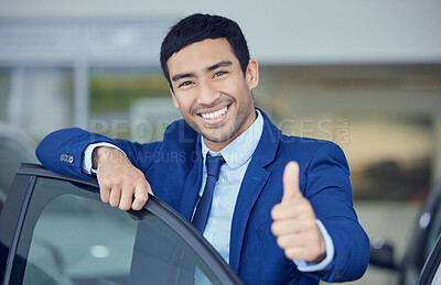 Buy stock photo Cropped portrait of a handsome young male car salesman giving thumbs up towards the camera while working on the showroom floor
