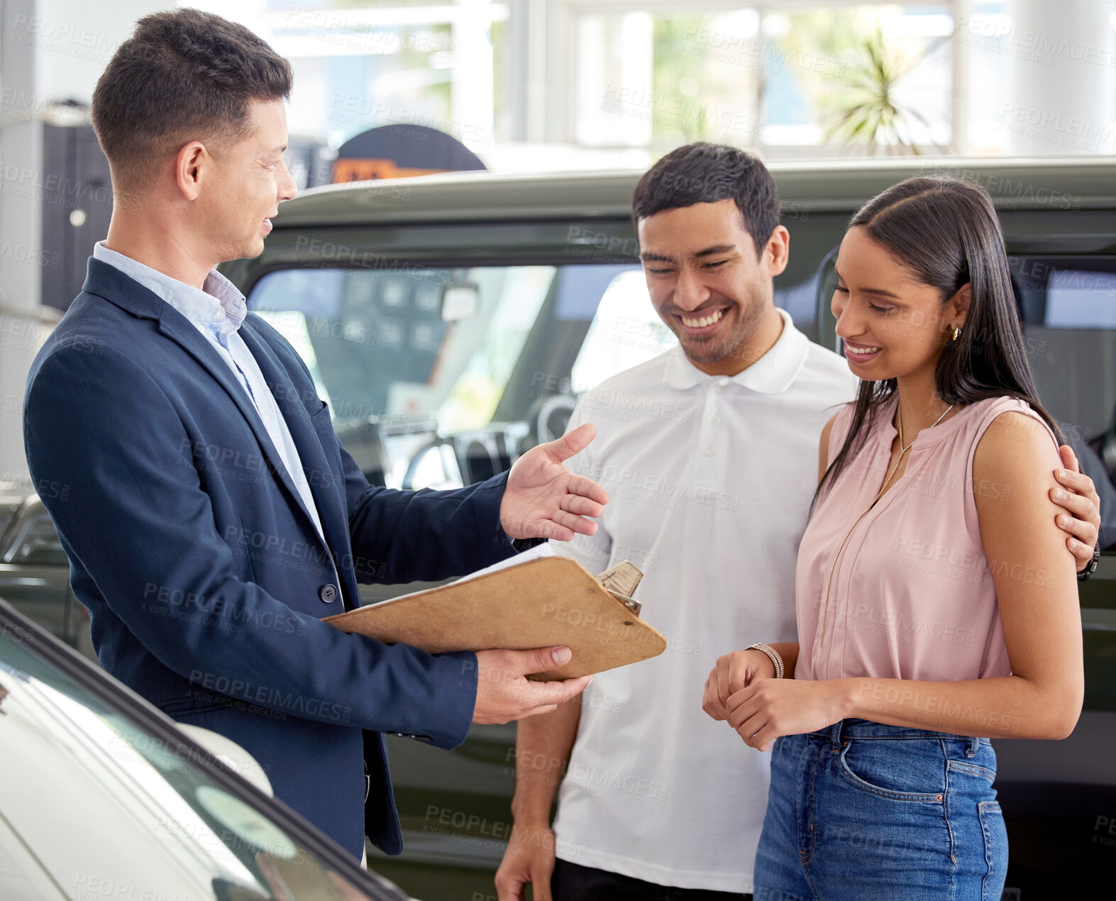 Buy stock photo Couple, car dealership and salesman with clipboard in discussion for and motor vehicle, sale and planning. Happy, man and woman with communication in showroom for automobile, service and application