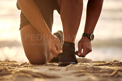 Buy stock photo Closeup shot of an unrecognisable man tying his laces while exercising at the beach