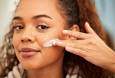 Buy stock photo Cropped shot of a beautiful young woman applying moisturiser to her face