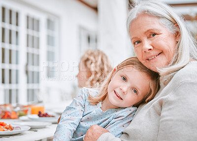 Buy stock photo Shot of a grandma and granddaughter cuddling at a table outside