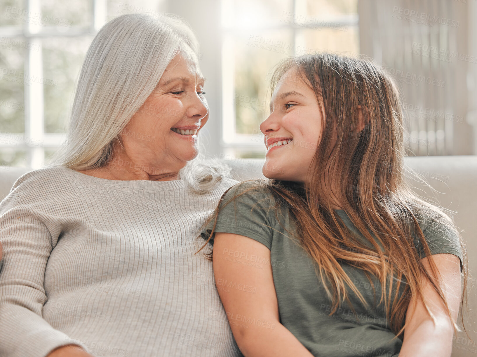 Buy stock photo Grandma, girl and happy on sofa for love, bonding and relationship development at home. Senior woman, grandchild and smily on couch for family values, womens day and weekend relax in living room