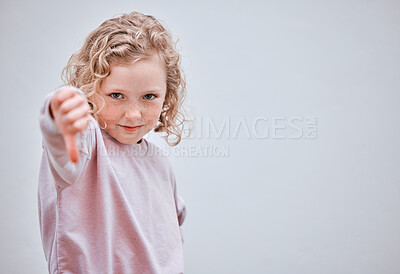 Buy stock photo Studio shot of a little girl showing thumbs down against a grey background