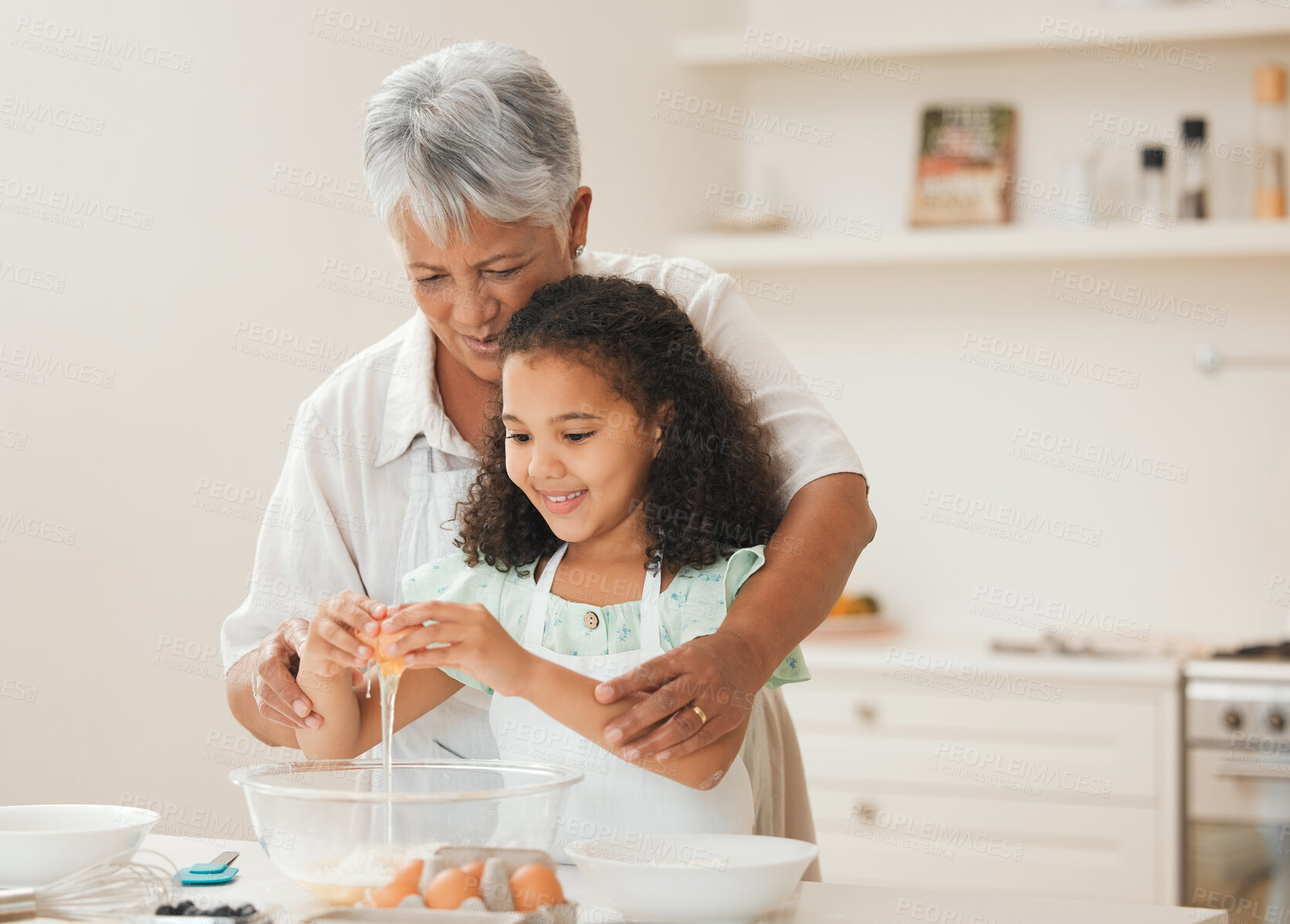 Buy stock photo Shot of a grandmother helping her granddaughter crack eggs into a bowl