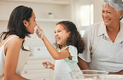 Buy stock photo Shot of a young girl playfully putting flour on her mothers nose during baking