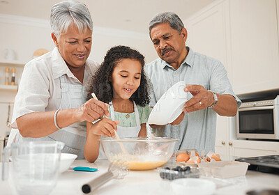 Buy stock photo Shot of a grandfather pouring flour into a bowl while his granddaughter bakes