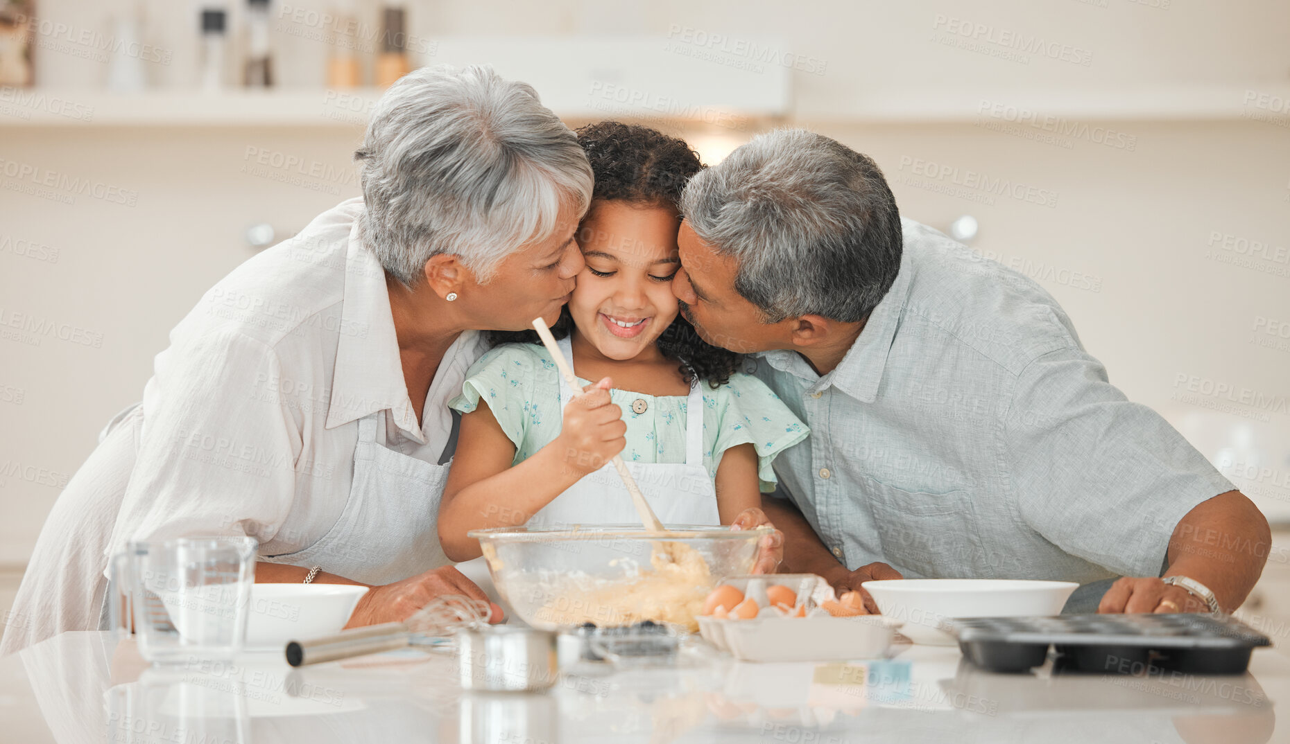 Buy stock photo Baking, kiss and grandparents with child in kitchen with ingredients for cake, cupcakes and dessert. Family, home and happy grandpa, grandma and girl embrace for bonding, relationship and learning